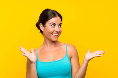 Yüzünde sürpriz ifade olan, izole edilmiş sarı arka planda genç bir kadın.