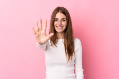 İzole edilmiş pembe arka plan üzerinde genç bir kadın parmaklarıyla beşi sayıyor