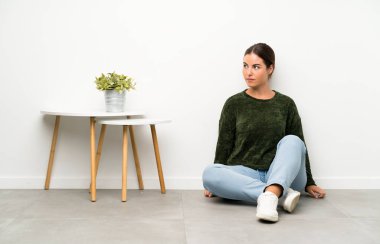 Genç kadın yan bakarak katta oturan