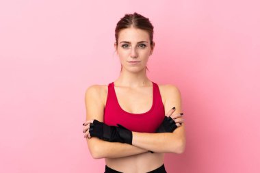 Soyutlanmış pembe arka planda kolları bağlı genç bir kadın.