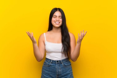 Genç Asyalı kız izole edilmiş sarı arka planda gülümsüyor.