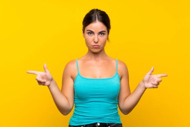 İzole edilmiş sarı arka planda genç bir kadın. Yan taraftakilerin şüpheleri var.