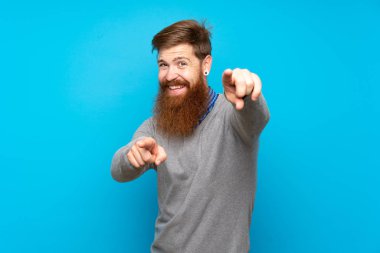 Mavi arka planda uzun sakallı kızıl saçlı adam gülümserken seni işaret ediyor.