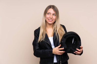 Motosiklet kasklı genç sarışın kadın izole bir arka planda gülüyor ve yukarı bakıyor.