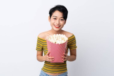 Genç Asyalı kız elinde koca bir kova patlamış mısır tutuyor.