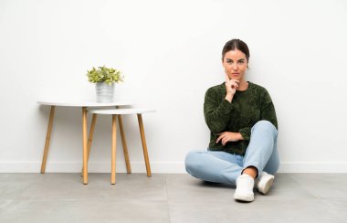 Genç bayan yerde oturmuş gülüyor.