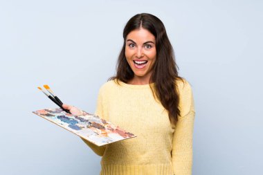 Soyutlanmış mavi arka planda, şaşırmış ve şok olmuş yüz ifadesi olan genç bir sanatçı.