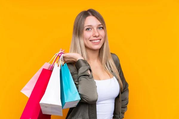 Ung Blond Kvinna Över Isolerad Gul Bakgrund Hålla Shoppingväskor Och — Stockfoto