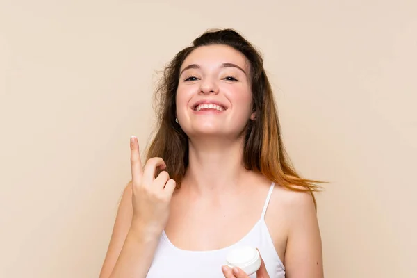 Menina morena jovem com hidratante sobre fundo isolado — Fotografia de Stock