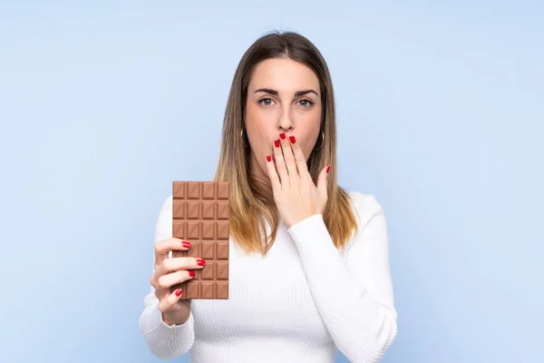 Mladá Blondýna Žena Přes Izolované Modré Pozadí Čokoládovou Tabletu Překvapený — Stock fotografie