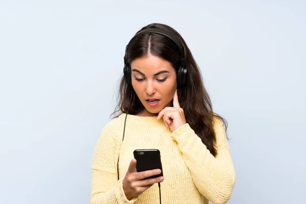 Jeune Femme Écoutant Musique Avec Mobile Sur Mur Bleu Isolé — Photo