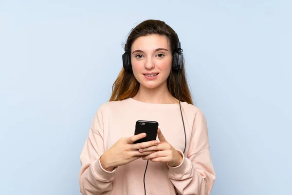 Fiatal Barna Lány Izolált Kék Háttér Segítségével Mobil Fejhallgatóval — Stock Fotó