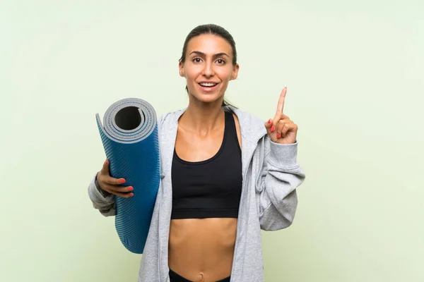 Joven Mujer Deportiva Con Alfombra Sobre Fondo Verde Aislado Apuntando — Foto de Stock