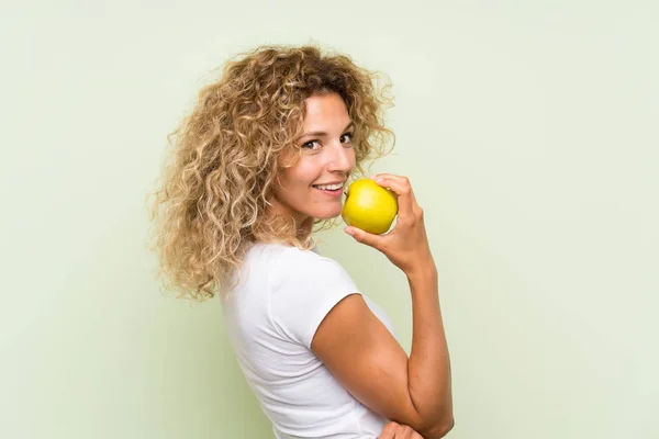 Junge blonde Frau mit lockigem Haar mit einem Apfel — Stockfoto