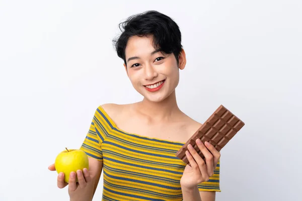 Mladá Asijská Dívka Brát Čokoládovou Tabletu Jedné Ruce Jablko Druhé — Stock fotografie