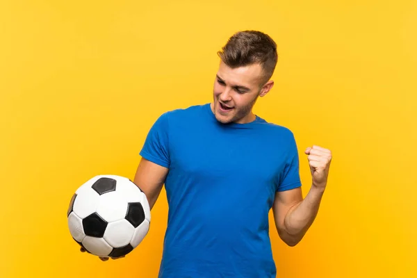 Νεαρός Όμορφος Ξανθός Άντρας Κρατά Μια Μπάλα Ποδοσφαίρου Πάνω Από — Φωτογραφία Αρχείου