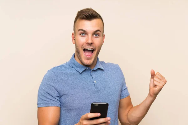 Szczęśliwy młody blond człowiek za pomocą telefonu komórkowego — Zdjęcie stockowe