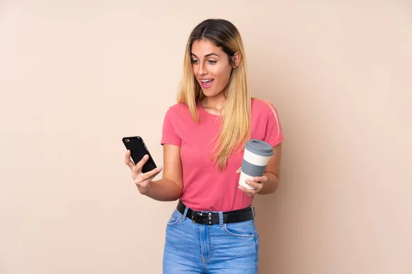 Jovem Uruguaia Sobre Fundo Isolado Segurando Café Para Levar Celular — Fotografia de Stock