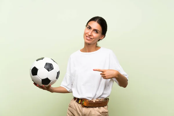 サッカーボールを持つ孤立した緑の背景の上の若い女性 — ストック写真
