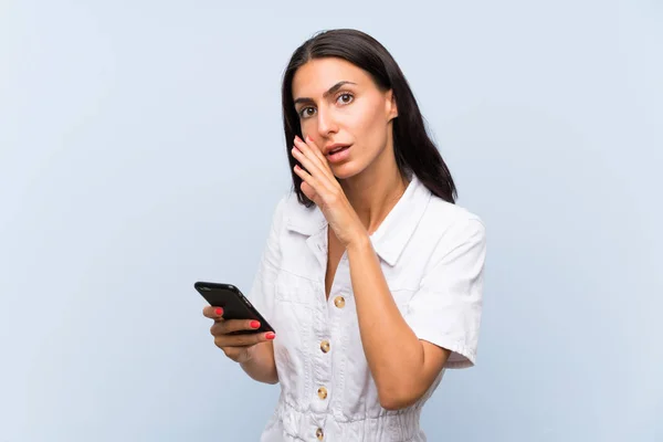 Mujer Joven Con Teléfono Móvil Sobre Una Pared Azul Aislada —  Fotos de Stock