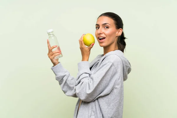 Giovane donna sportiva con una mela e con una bottiglia di wate — Foto Stock