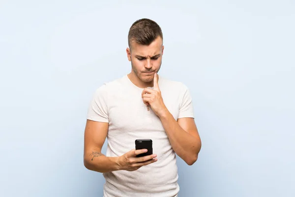 Junge Hübsche Blonde Mann Über Isolierten Blauen Hintergrund Mit Mobiltelefon — Stockfoto