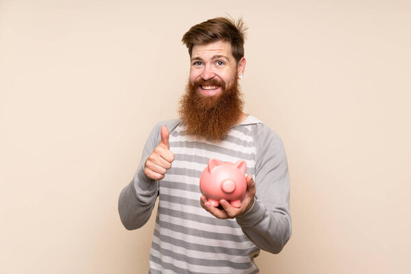 Redhead man with long beard over isolated background holding a big piggybank