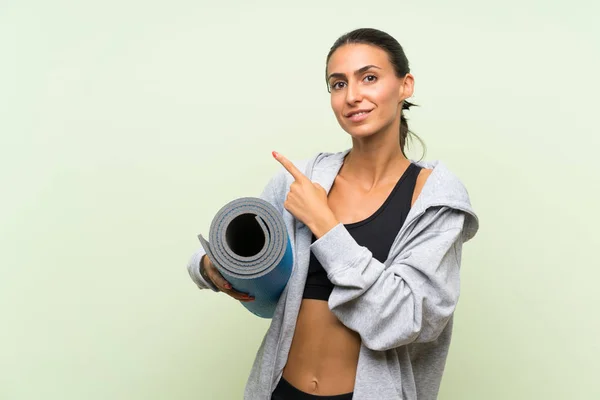 Giovane Donna Sportiva Con Stuoia Sfondo Verde Isolato Che Punta — Foto Stock