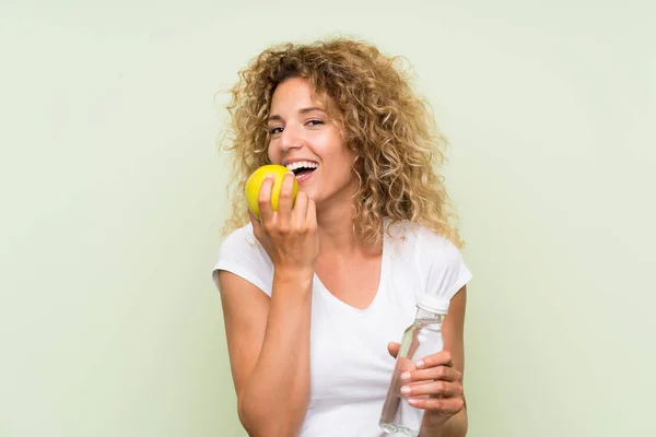 Young blonde woman with curly hair with an apple and with a bottle of water — Stock Photo, Image