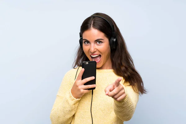 Молодая Женщина Слушает Музыку Мобильного Над Изолированной Синей Стеной — стоковое фото