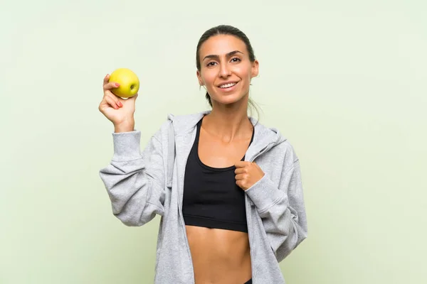 Jonge Sportvrouw met een appel over geïsoleerde groene achtergrond — Stockfoto