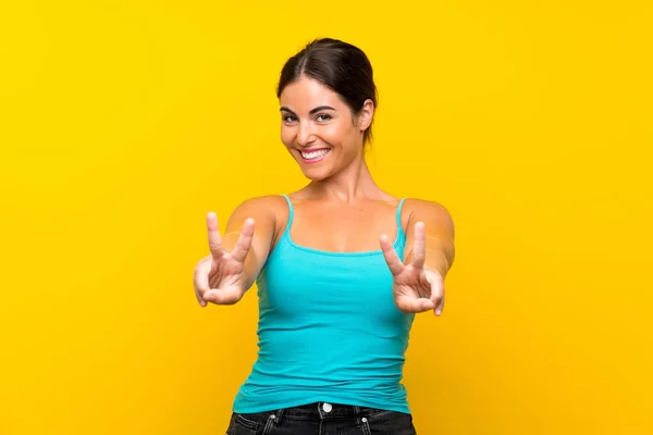 Młoda Kobieta Odizolowanym Żółtym Tle Uśmiecha Się Pokazuje Znak Zwycięstwa — Zdjęcie stockowe