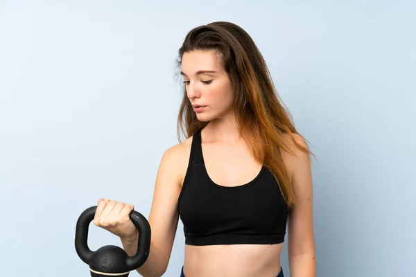 Jovem morena fazendo levantamento de peso com kettlebell sobre fundo isolado — Fotografia de Stock