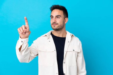 Soyutlanmış mavi arka plan üzerinde genç yakışıklı adam şeffaf ekrana dokunuyor