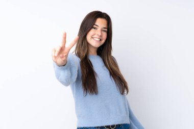 Izole beyaz arka plan üzerinde Genç kız gülümseyerek ve zafer işareti gösteren