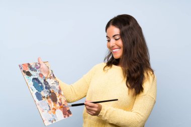 Izole mavi arka plan üzerinde genç sanatçı kadın