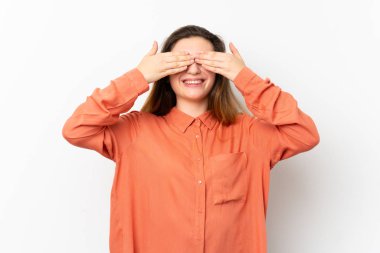 İzole edilmiş beyaz arka planda genç esmer kız gözlerini elleriyle kapatıyor.