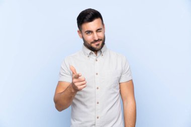 Sakallı, mavi arka planda genç ve yakışıklı bir adam.