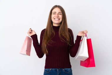 Soyutlanmış beyaz arka planda genç bir kadın alışveriş torbaları tutuyor ve gülümsüyor.