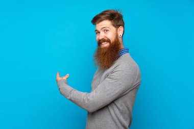 Kızıl saçlı, uzun sakallı, izole edilmiş mavi arka planı olan bir adam.