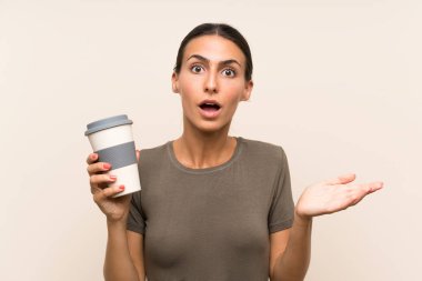 Elinde şok olmuş bir yüz ifadesiyle kahve taşıyan genç bir kadın.