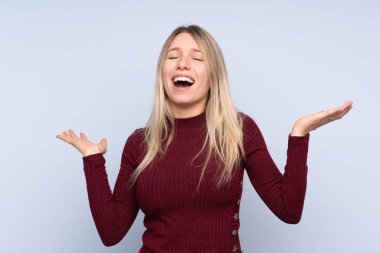 Izole mavi arka plan üzerinde genç sarışın kadın çok gülümsüyor