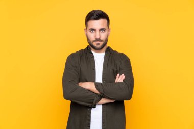 İzole edilmiş sarı arka plandaki adam kollarını kavuşturuyor.