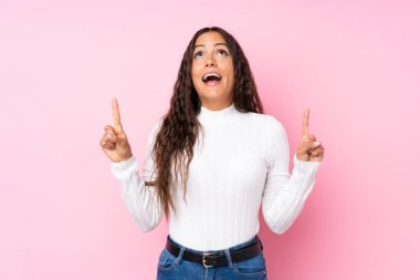 Soyutlanmış pembe arka planı olan genç bir kadın şaşırmış ve yukarı bakıyor.
