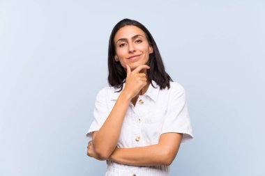 Genç bir kadın mavi arka planda gülüyor.