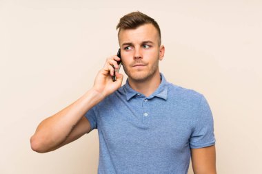 Genç sarışın adam cep telefonu kullanıyor.