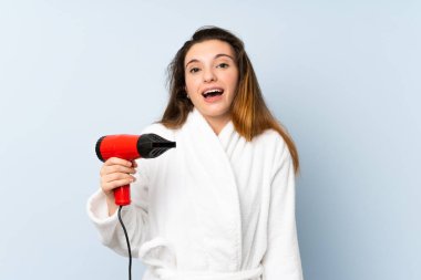 Bornozlu, saç kurutma makineli, şaşırmış ve şok olmuş yüz ifadesi olan genç bir kadın.