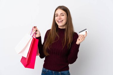 Soyutlanmış beyaz bir geçmişi olan genç bir kadın, elinde alışveriş çantaları ve bir kredi kartı tutuyor.