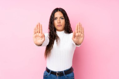 Soyutlanmış pembe arka planı olan genç bir kadın dur hareketi yapıyor ve hayal kırıklığına uğruyor.