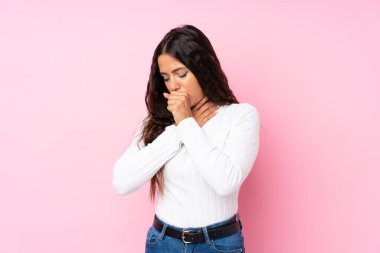 Soyutlanmış pembe arka planı olan genç bir kadın öksürük ve kötü hissetmekten muzdarip.